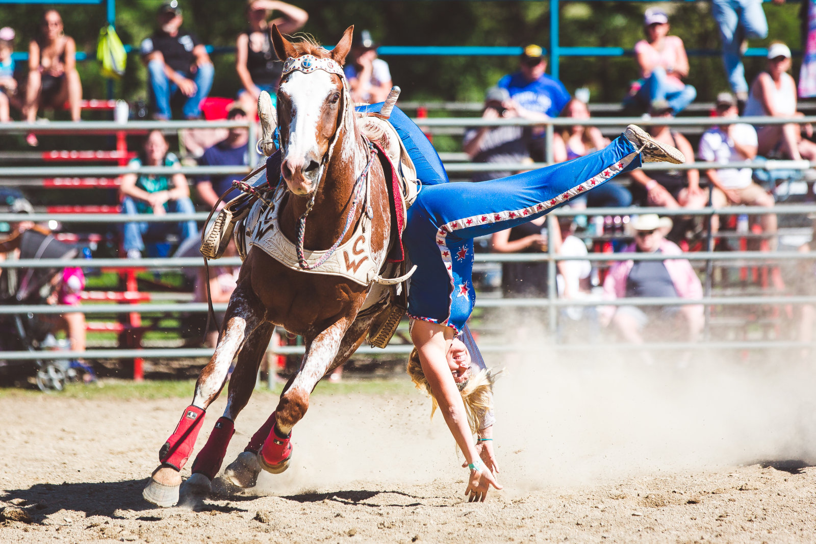 Cowgirls and cowboys holding sponsor flags on horseback in July 2018